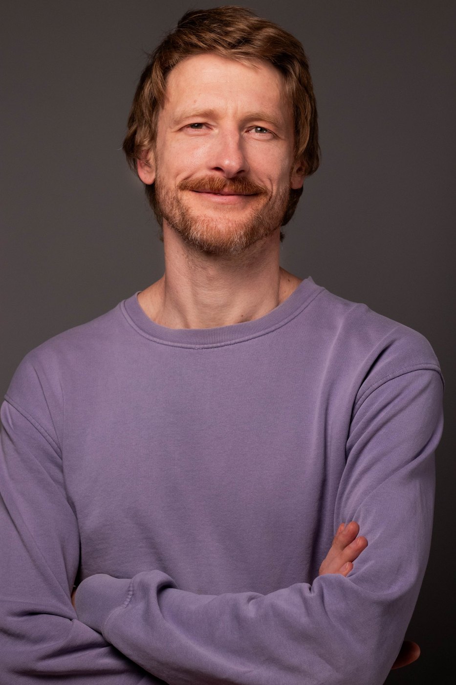 Alex, portrait in a lavender sweater with arms crossed