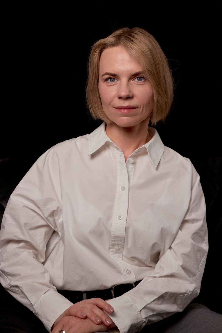 Olha, seated portrait in a white shirt against a black backdrop