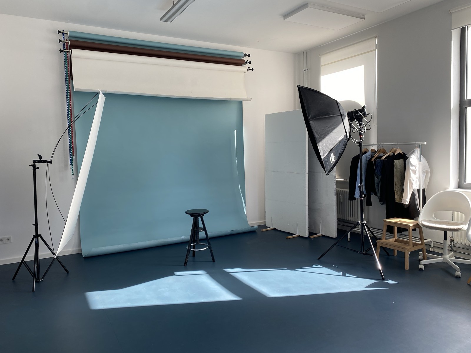 The studio with a blue backdrop, softbox and clothing rail